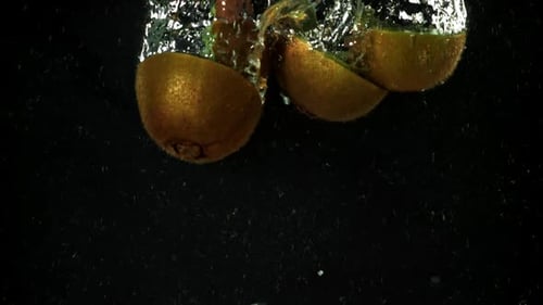Kiwi Fruit Slices Falling into Water in Slow Motion
