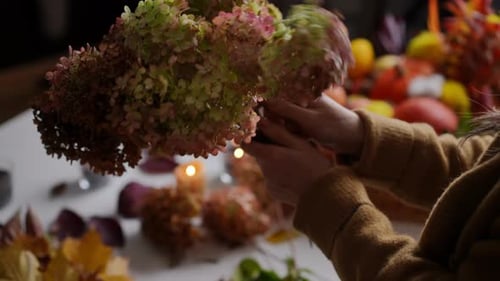 Person Arranging Flowers and Foliage at Table