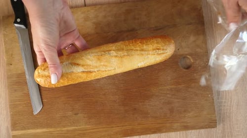 Woman Slicing Baguette on Wooden Cutting Board