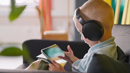 Child Using Tablet Device with Headphones at Home