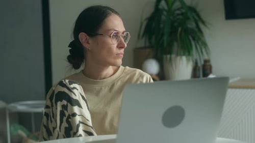 Woman With Laptop Looking Out Window at Home