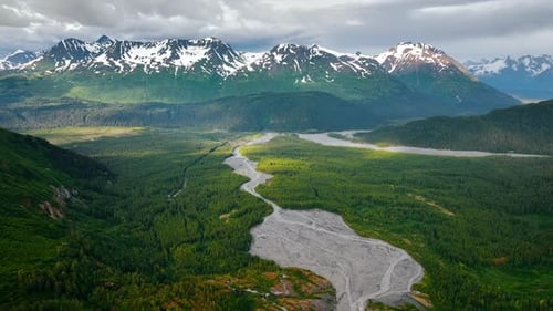Green woods covering the valley crossed by the shallow river.