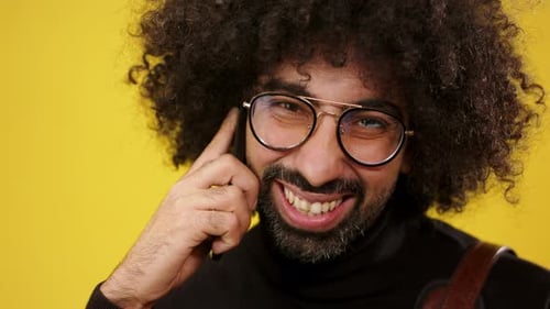 Closeup Shot Of Mature Man With Smartphone In A Studio On Yellow Background.