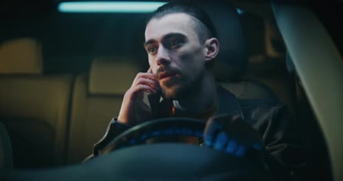 Man Sitting in Car Talking on Phone at Night