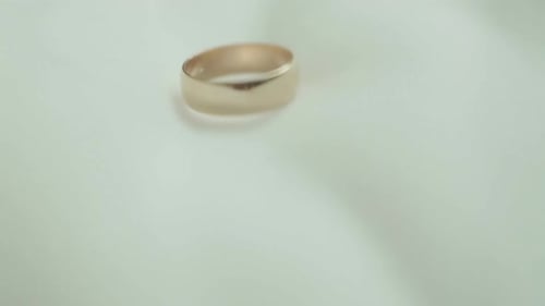 Studio Shot of Two Wedding Rings Falling Against White Background