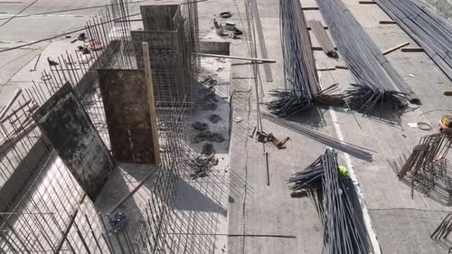 Vista aérea de un ajetreado sitio de construcción con trabajadores doblando barras de refuerzo y preparando los cimientos