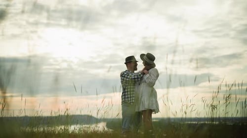 Romantic Couple Embracing in a Grass Field Under a Cloudy Sky