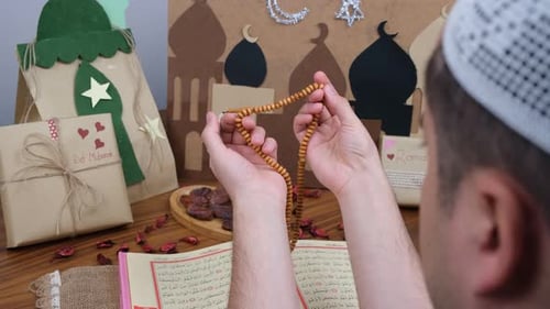 Man Holding Prayer Beads with Ramadan Decorations