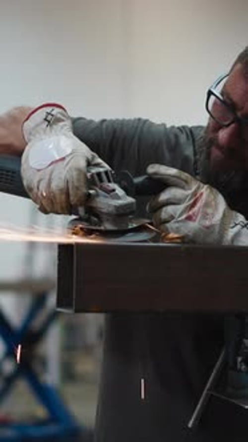 Metalworker Grinding Steel Beam with Angle Grinder