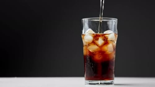 Pouring Dark Soda in a Glass with Ice