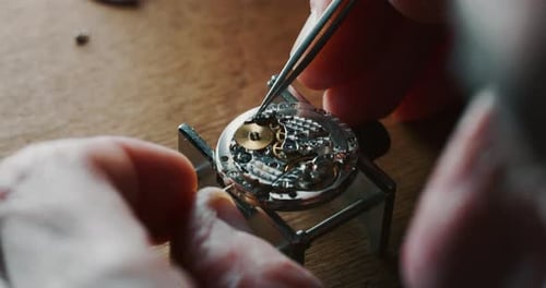 Slow motion close up of a professional watchmaker repairer working on a luxury mechanism watch gea
