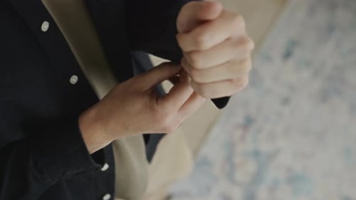 Man Buttoning Sleeve of Dark Blue Shirt Indoors