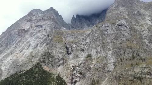 Stunning 4k drone footage panning across the high mountain peaks revealing a glacier and water falls