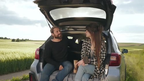 Young Couple Chatting in Open Car Trunk in Countryside