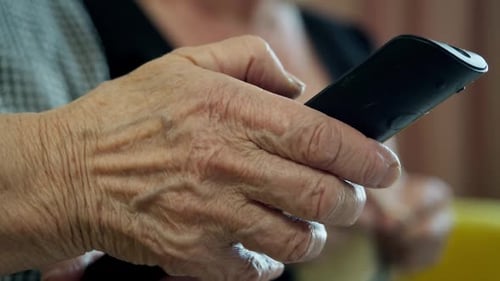 Anciana que sostiene un mando a distancia