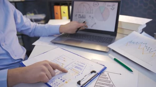 Person Analyzing Business Charts at Desk