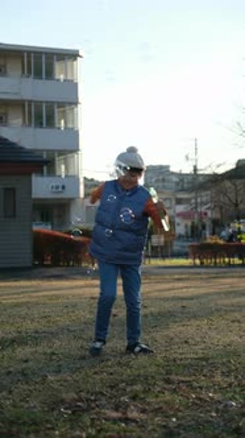 Japanese boy playing and blowing soap bubbles in a park