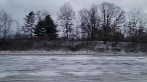 Eine Aufnahme einer verschneiten Landschaft mit Bäumen und einer Straße, die die kalte und ruhige Winterlandschaft einfängt.