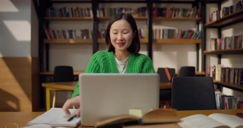 Focused Brunette Student Girl in a Green Sweater Comes to a Decision While Studying in Front of a