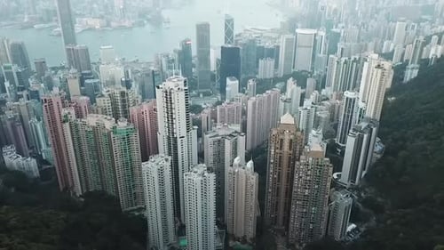 Aerial: Hong Kong City Skyscrapers from the Mountain Behind to the Harbor Ahead