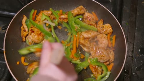 Overhead View of Chef Hand Moving Chinese Stir Fry Meal Around Pan with Marinated Chicken Pieces