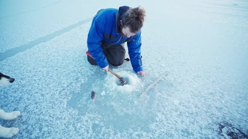Ein Loch in einen gefrorenen See zum Eisfischen bohren
