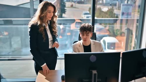 Business session in an office. Young man is using computer and discussing business affairs. Slow mot