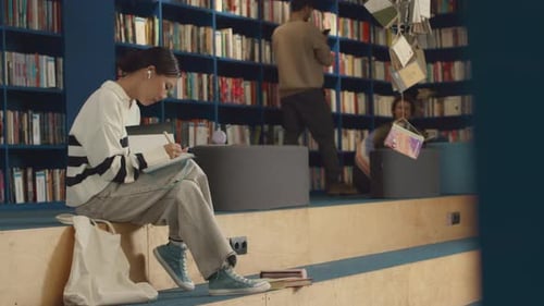 Asiatisches Mädchen macht Hausaufgaben in der College-Bibliothek