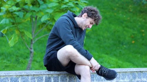 Caucasian Man Sitting and Massaging His Leg in Green Park Sportsman Feeling Strong Pain in His Ankle