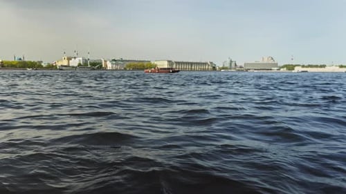 Boot auf dem Wasser vor dem Hintergrund des Stadtbildes, Wellen