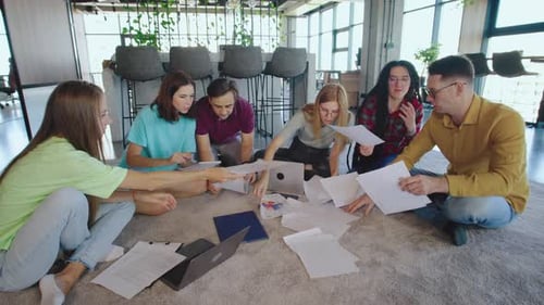 Team Collaborating on Floor in Modern Office Space