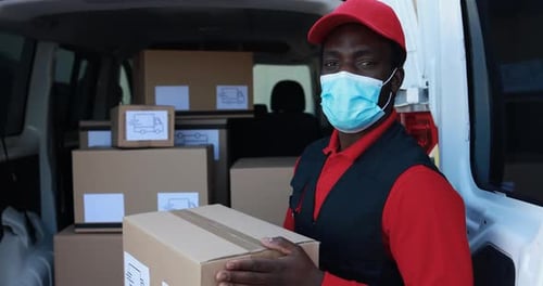 African Man Courier Delivering Packages with Truck While Wearing Safety Face Mask