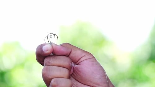 Fishing hook hold by hand showing on the camera