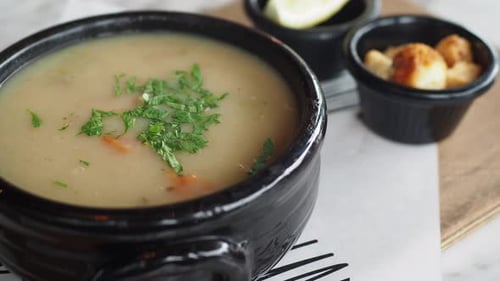 Hearty Bowl of Soup with Garnish on Table