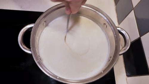 Un homme mélange du porridge crémeux à la semoule dans une casserole - Vue de la cuisine du haut vers le bas