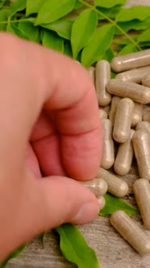 Supplement Capsules with Green Leaves on Wood Background