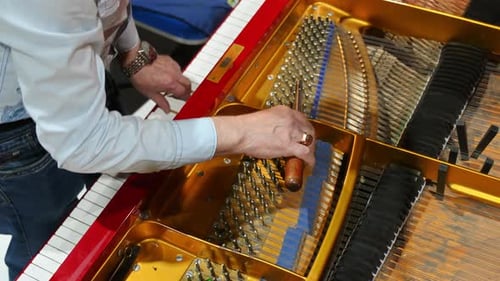 Close up of a man fixing a red piano