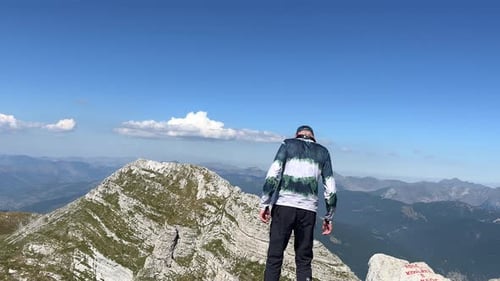 A Male Tourist Approaches the Edge of a Mountain Peak and in a Fit of Happiness Spreads His Arms to