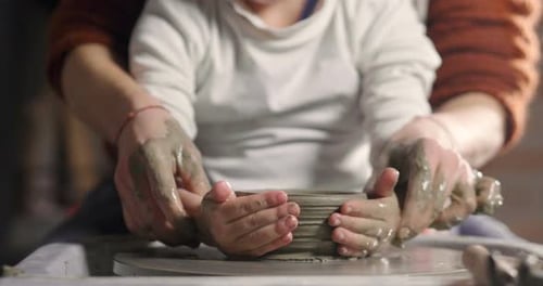 Child Learning Pottery with Adult Guidance