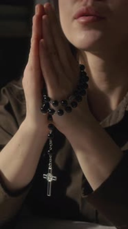 Woman in Prayer Holding a Rosary Beads