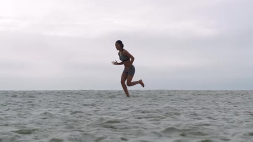 Fitness, woman and running on beach, sand and ocean for cardio exercise