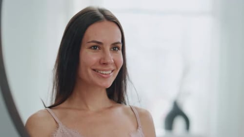 Woman Smiling in Mirror in Bright Indoor Setting