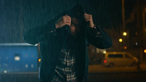Young Caucasian Man Wearing Square Shirt Using His Jeans Jacket as a Raincoat. Scene is Shot in a C