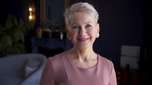 Elderly Businesswoman Looking Forward and Smiling While Standing in Modern Office Akspb