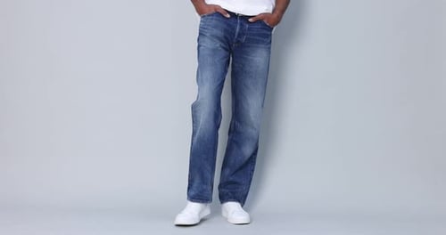 Man in Jeans Posing in Front of Grey Backdrop