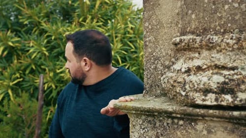 Homem se escondendo atrás de uma coluna olhando ao redor