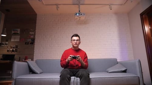 Man Plays Video Game on Couch at Home