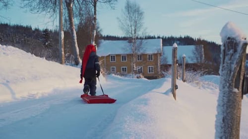 Un petit garçon tire un traîneau un jour de Noël en hiver en Norvège