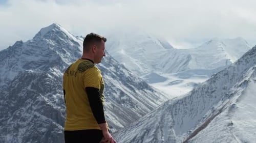Man Standing Atop Snowy Mountain Peaks
