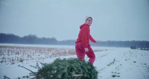 Homme heureux tirant un sapin de Noël tout en courant sur un paysage enneigé